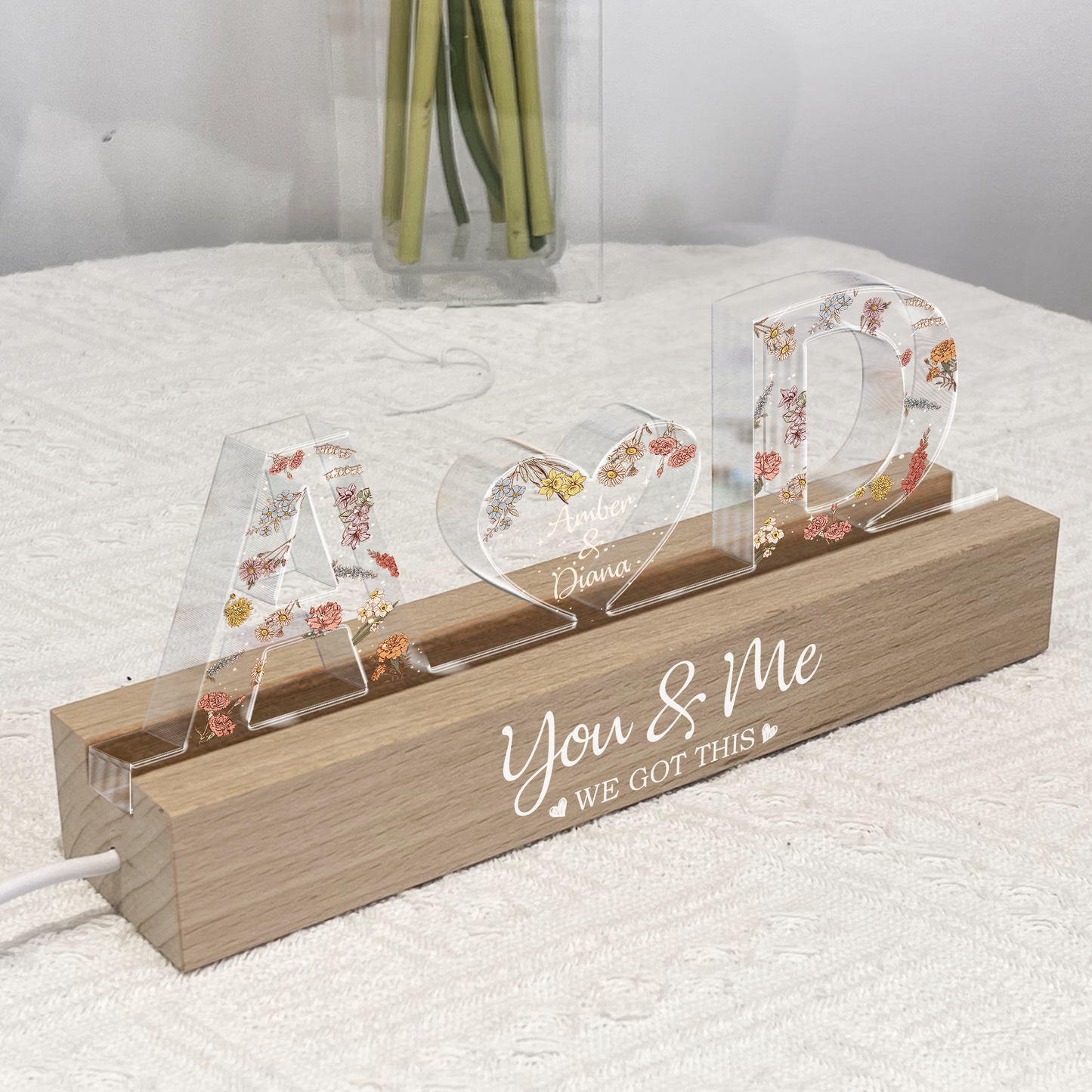 Personalized acrylic LED lamp with floral letters and custom couple names in heart shape.