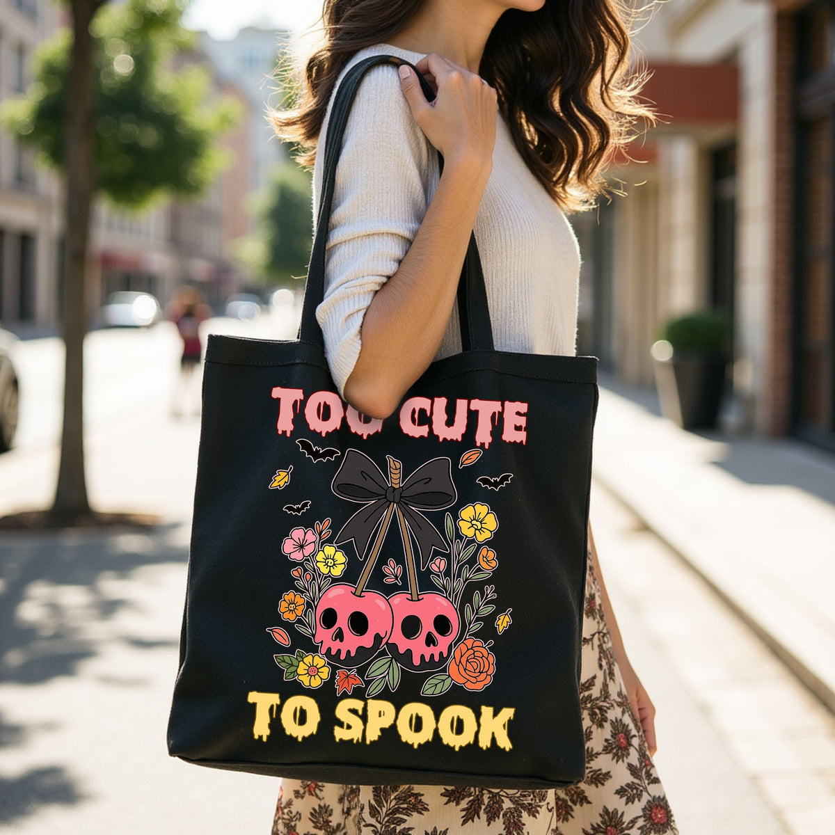 Person holding a black tote bag with Halloween design and text on a city street.